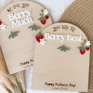 May include: Two wooden plaques with arched tops, decorated with strawberries and leaves. One says "We Love You Berry Much," and the other says "You Are The Berry Best." Both have "Happy Mother's Day!" and a name.