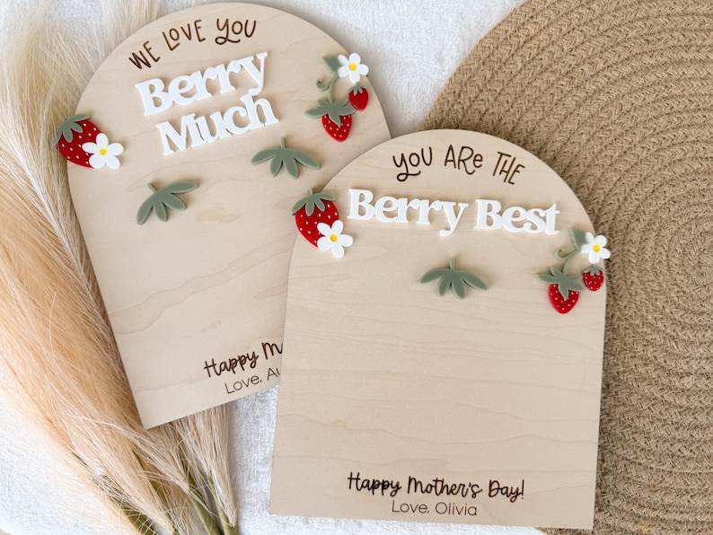 May include: Two wooden plaques with arched tops, decorated with strawberries and leaves. One says "We Love You Berry Much," and the other says "You Are The Berry Best." Both have "Happy Mother's Day!" and a name.