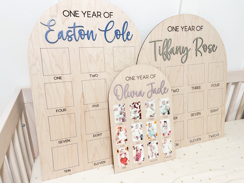 Wooden birthday boards with arched tops. The boards are engraved with the words "ONE YEAR OF" and a have a name in 3D. Each board has spaces for photos labeled with numbers. The smallest board displays photos of a baby.
