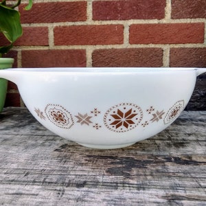 Puede incluir: Tazón blanco para mezclar con un patrón geométrico marrón y blanco. El tazón tiene un borde ancho y dos asas.