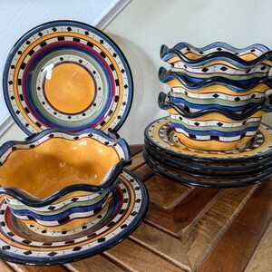 May include: Set of four colorful ceramic bowls with scalloped edges and a matching plate. The bowls and plate feature a multi-colored design with black, yellow, blue, green, and red accents.
