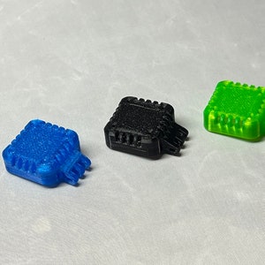 May include: Three 3D printed square-shaped objects with a textured surface. The objects are blue, black, and green.