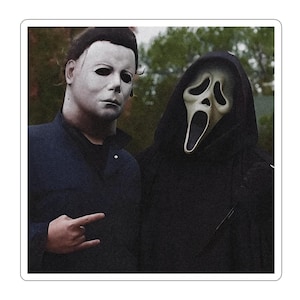 May include: A sticker featuring two figures: one wearing a white, expressionless mask with dark hair and a dark blue collared shirt, and the other wearing a black hooded robe with a pale, elongated ghost mask with a wide, open mouth expression.