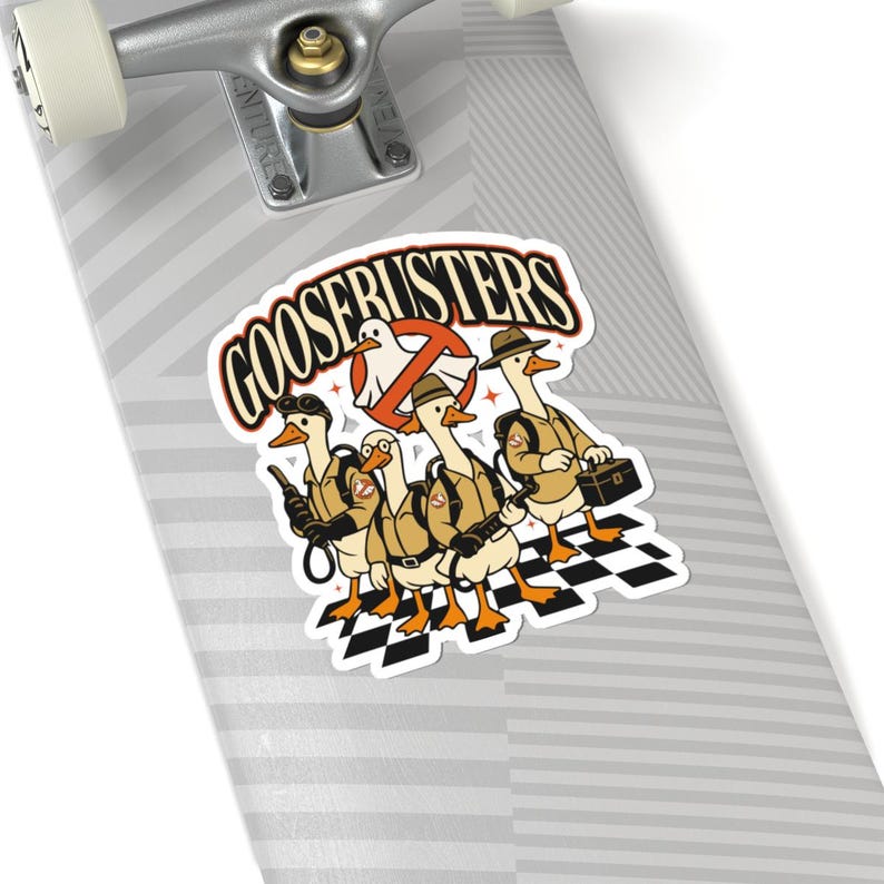 Pode incluir: Um autocolante com o texto "GOOSEBUSTERS" e uma ilustra&ccedil;&atilde;o de quatro patos vestidos como os Ca&ccedil;a-Fantasmas. Eles usam uniformes c&aacute;qui, mochilas de pr&oacute;tons e chap&eacute;us, com um deles segurando uma maleta. O fundo inclui um padr&atilde;o xadrez em preto e branco.