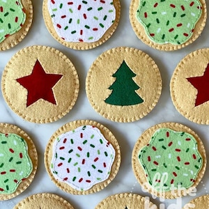 May include: Overhead shot of felt Christmas cookies. Some have green frosting with red and green sprinkles, others have white frosting with sprinkles. Some have a red star or green Christmas tree design.
