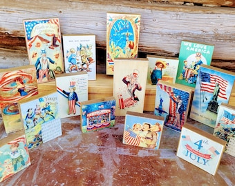 May include: A collection of 14 small wooden blocks with patriotic images and text. The blocks feature images of the American flag, Uncle Sam, fireworks, and other patriotic symbols. The text on the blocks includes phrases like "Fourth of July Greetings", "We Love America", and "Yankee Doodle".