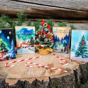 May include: Four wooden Christmas ornaments with vintage illustrations and text. The ornaments feature a snowy scene with a train, a Christmas tree, a starry night scene, and a Christmas tree with the text "It's not what's under the tree that matters, it's who is around it".