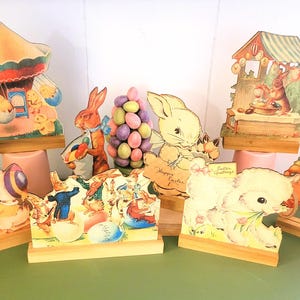 May include: A set of eight vintage Easter-themed cardboard stand-up decorations. The decorations feature a variety of characters, including bunnies, chicks, and a carousel. The decorations are all painted in bright colors and have a whimsical feel.  Happy Easter Greetings.
