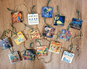 Peut inclure: Un collier de perles de Mardi Gras avec divers ornements carrés représentant des images de la Nouvelle-Orléans, des célébrations du Mardi Gras et des textes comme "Mardi Gras Beads & Masks King Cake Parades" et "We Don't Hide The Crazy We Parade It Down The Street".