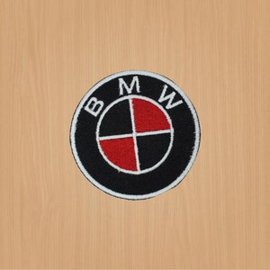 Peut inclure: Patch brodé noir et blanc avec le logo BMW. Le logo présente un cercle blanc avec un design d'hélice noir et rouge à l'intérieur. Les lettres "BMW" sont en blanc et entourent le cercle.