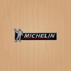 May include: Black and white embroidered patch featuring a Michelin Man figure and the word "MICHELIN" in white lettering on a black background.