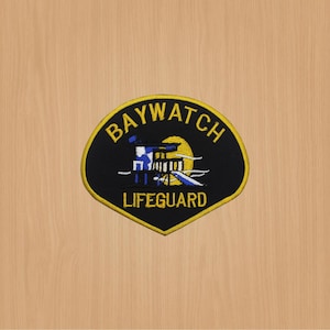 May include: Black and yellow embroidered patch with the words "BAYWATCH LIFEGUARD" and a graphic of a lifeguard stand with a lifeguard flag and a sun.
