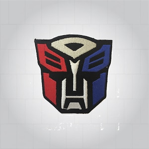 以下が含まれることがあります： 赤、白、青の刺繍パッチで、トランスフォーマーのロゴが描かれています。ロゴは、黒い背景にスタイリッシュなロボットの顔が描かれています。
