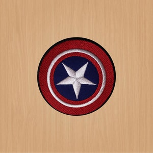May include: A red, white and blue embroidered patch with a white five-pointed star in the centre. The patch is circular and has a black border.