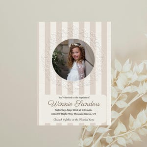 May include: A rectangular invitation card featuring a beige and white vertical striped background with a central circular frame containing a photograph of a child. The text reads: You're invited to the baptism of Winnie Sanders, Saturday, May 22nd at 9:30 a.m., 8888 CT Right Way Pleasant Grove, UT, Brunch to follow at the Sanders home.
