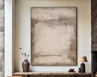 May include: Abstract painting in shades of beige, gray, and brown with a textured finish. The painting is framed in a black frame and hangs on a white wall above a wooden shelf.