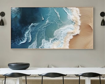 May include: An aerial photograph of ocean waves crashing on a sandy beach. The water is a deep blue and the sand is a light beige. The waves are white and foamy.