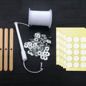 May include: A set of candle making supplies including wooden candle wicks, a white wick sticker, a spool of white cotton wick, a pile of silver candle cups, and a sheet of white adhesive candle stickers.