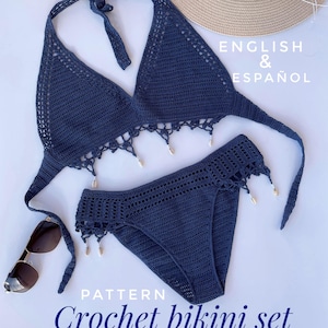 May include: A crochet bikini set in a dark blue color. The top is a halter style with a fringe trim and the bottom is a high-waisted style with a similar fringe trim. The set is made with a soft, lightweight yarn and is perfect for a day at the beach.