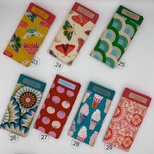 May include: A collection of eight rectangular fabric cases with various patterns. Designs include butterflies, geometric shapes, and ice cream cones. Each case has a colored top and a "HANDMADE" label.