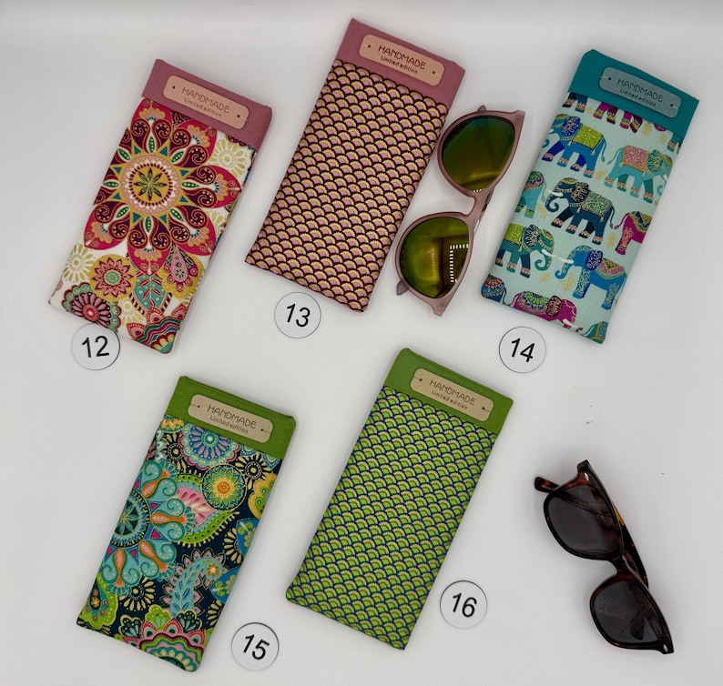 May include: A collection of handmade eyeglass cases in various patterns and colors. Designs include floral, geometric, and elephant prints. Some cases have the word "HANDMADE" on them. Sunglasses are also included.