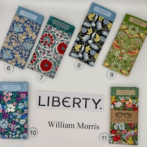 May include: A collection of fabric eyeglass cases with floral and botanical patterns. The cases are labeled with the text "HANDMADE" and "LIBERTY. William Morris". The cases are in various colors, including blue, red, green, and floral prints.