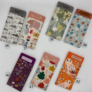 May include: A collection of handmade glasses cases with various fabric patterns. Designs include rabbits, bears, trees, leaves, and owls. Each case has a rectangular shape with a top flap labeled "HANDMADE Limited Edition".
