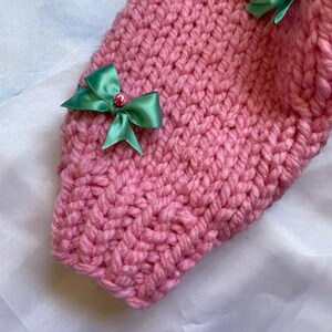 May include: Pink knitted fabric with green bows and small pink beads. The fabric is soft and fluffy.