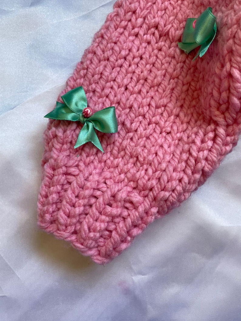 May include: Pink knitted fabric with green bows and small pink beads. The fabric is soft and fluffy.