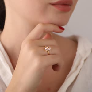 May include: A gold ring with a large, rectangular, light pink gemstone.