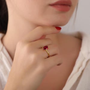 Könnte beinhalten: Ein goldener Ring mit einem großen, ovalen, roten Edelstein.