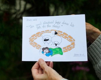 Könnte beinhalten: Eine weiße Karte mit einer handgezeichneten Illustration eines schlafenden Hirten mit drei Schafen in einem Stall. Die Karte trägt den Text "Jesus sagte: "Der gute Hirte gibt sein Leben für die Schafe." Johannes 10:11"