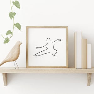 May include: A framed black and white line drawing of a person in a martial arts pose, on a wooden shelf with a wooden bird figurine and a potted plant.