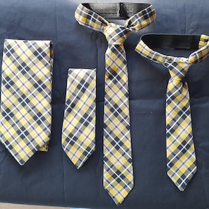 May include: Three yellow and black plaid ties with adjustable neck straps. The ties are different lengths.