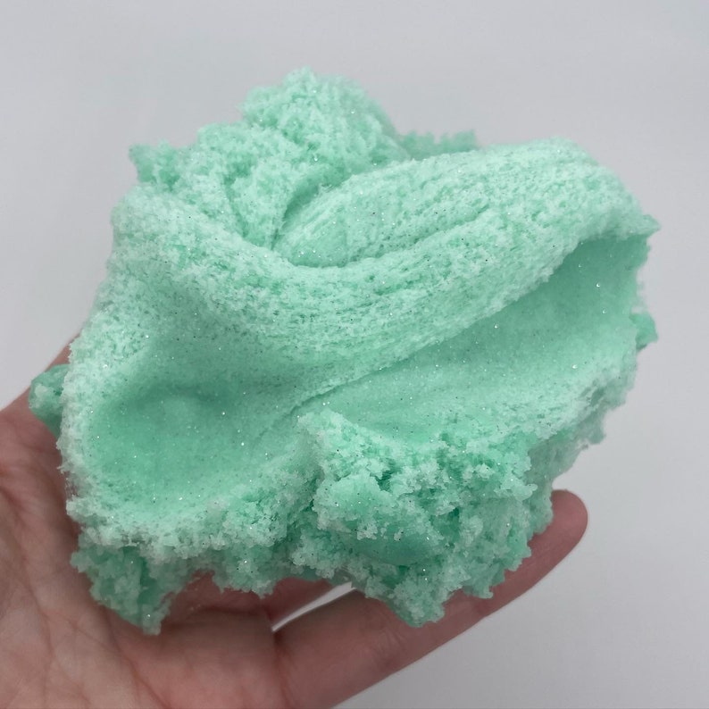 May include: A light green slime with a sparkly texture. The slime is soft and fluffy, and it looks like it would be fun to play with.