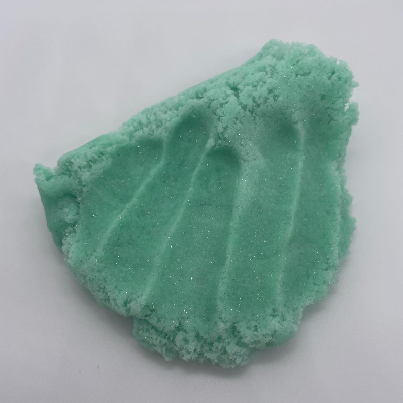 May include: A close-up of a light green, glittery slime. The slime is textured and has a slightly rough surface.