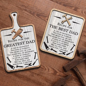 May include: Two wooden signs with a whitewashed background and black text. The signs are shaped like a cutting board and a square. Both signs have a recipe for "The Best Dad" and "The Greatest Dad" with a list of ingredients like "a can of protection", "two cups of patience", and "a dash of courage".