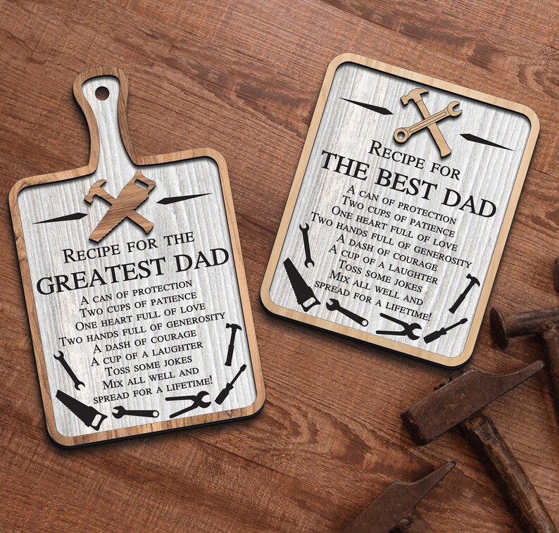 May include: Two wooden signs with a whitewashed background and black text. The signs are shaped like a cutting board and a square. Both signs have a recipe for "The Best Dad" and "The Greatest Dad" with a list of ingredients like "a can of protection", "two cups of patience", and "a dash of courage".