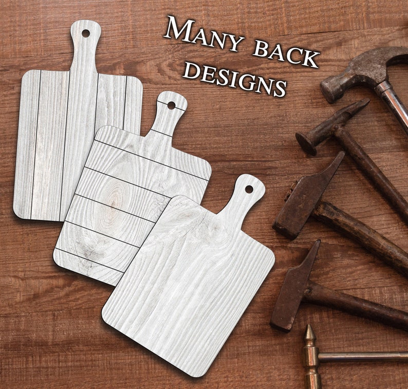 May include: Three white wooden cutting boards with different wood grain patterns. The boards have a handle on the top and are arranged on a brown wooden surface. The text "MANY BACK DESIGNS" is visible in the top right corner of the image.