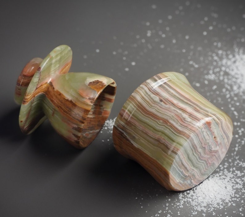 May include: Two green, brown, and white striped onyx salt and pepper shakers. The salt shaker is a round, squat shape, while the pepper shaker is a taller, more conical shape.