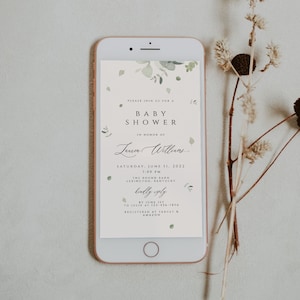 Puede incluir: Un teléfono inteligente que muestra una invitación a un baby shower con un diseño floral verde. La invitación dice "Por favor, únase a nosotros para un baby shower en honor a Laner Williams. Sábado, 11 de junio de 2022, 1:00 PM, The Round Barn, Lexington, Kentucky. Por favor, confirme su asistencia antes del 1 de junio a Julie al 123-456-7890. Registrado en Target & Amazon."