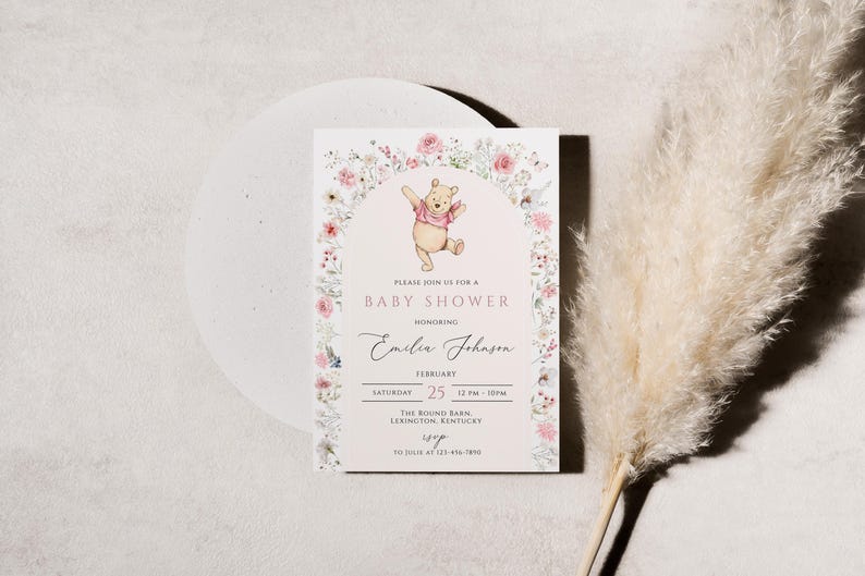 Pode incluir: Um convite para ch&aacute; de beb&eacute; com uma ilustra&ccedil;&atilde;o de Winnie the Pooh. O convite tem um design de arco floral com o texto "Baby Shower" e detalhes para o ch&aacute; de beb&eacute; de Emilia Johnson. O convite est&aacute; em um fundo branco.