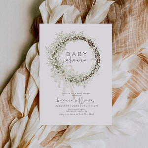 Può includere: Un biglietto bianco con un disegno di una ghirlanda floreale e il testo "BABY SHOWER" in corsivo nero. Il biglietto include anche il testo "join us for a baby shower honoring Brianna Williams August 14, 2023 at 2:00 pm the round barn, Lexington, Kentucky RSVP to Katie at 245-754-5684"