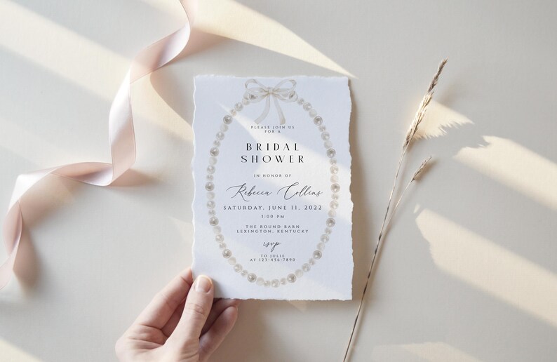 May include: A white bridal shower invitation with a pearl necklace design. The invitation reads "Please join us for a Bridal Shower in honour of Rebecca Collins, Saturday, June 11, 2022, 1:00 PM, The Round Barn, Lexington, Kentucky."