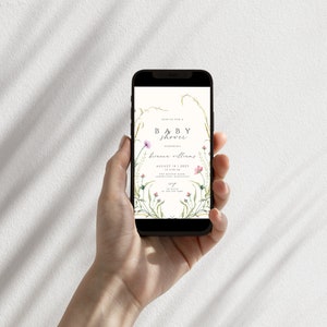May include: A smartphone displaying a baby shower invitation with a floral design. The invitation reads "Join us for a Baby Shower honoring Brianna Williams, August 14, 2023, at 2:00 PM, The Boling Barn, 12345 Somewhere, Anywhere".