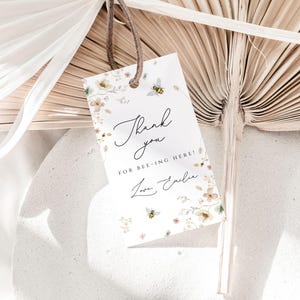 May include: A white thank you tag with a floral design and bees. The tag says "Thank you for bee-ing here! Love, Emily".