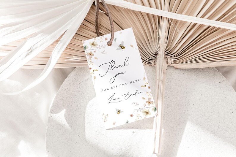 May include: A white thank you tag with a floral design and bees. The tag says "Thank you for bee-ing here! Love, Emily".
