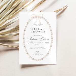 May include: A white bridal shower invitation featuring a pearl necklace design and the text "Please join us for a Bridal Shower in honour of Rebecca Collins Saturday, June 11, 2022 1:00 PM The Round Barn Lexington, Kentucky RSVP at 123-456-7890"