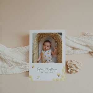 Op de afbeelding: Een witte kaart met een foto van een baby in een rieten mand. De kaart heeft een geel honingraatpatroon met bijen en bloemen. De tekst op de kaart luidt "Olivia Williams 06 | 12 | 2022".
