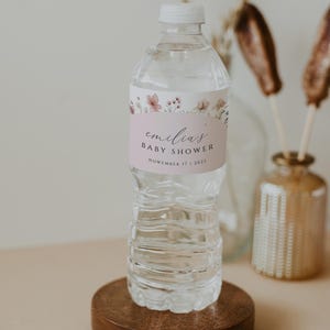 May include: A clear plastic water bottle with a pink and white floral label that says "emilia's baby shower November 17 | 2023".